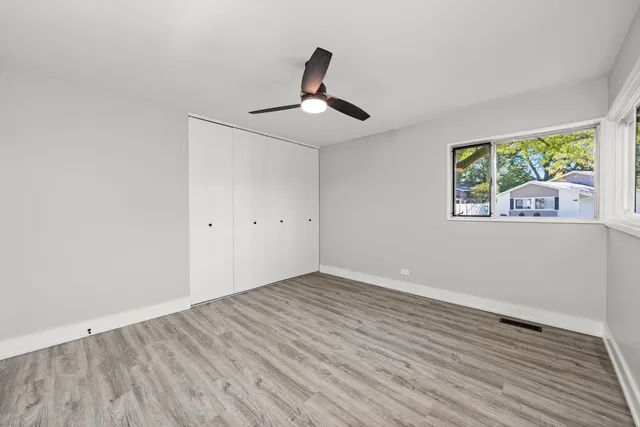 a view of empty room with wooden floor and fan