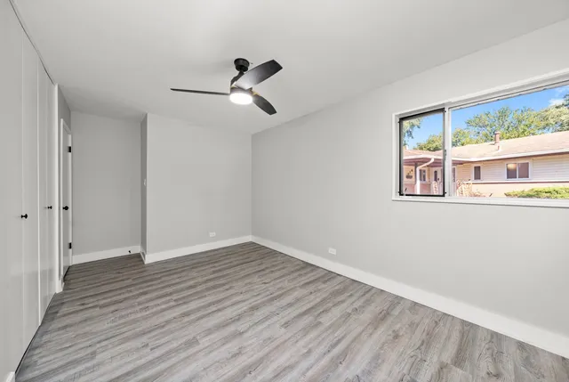 a view of empty room with wooden floor and fan
