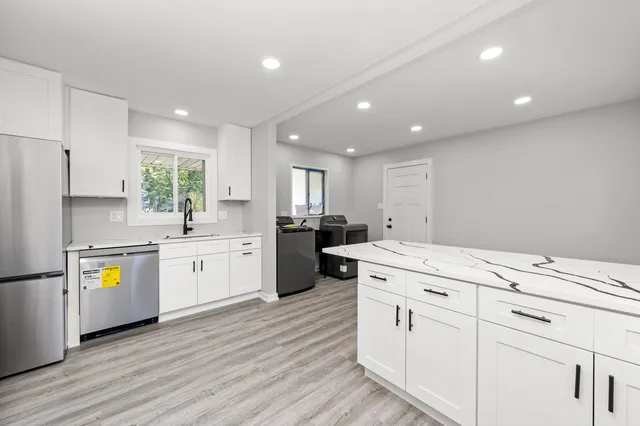 a kitchen with white cabinets appliances and wooden floor