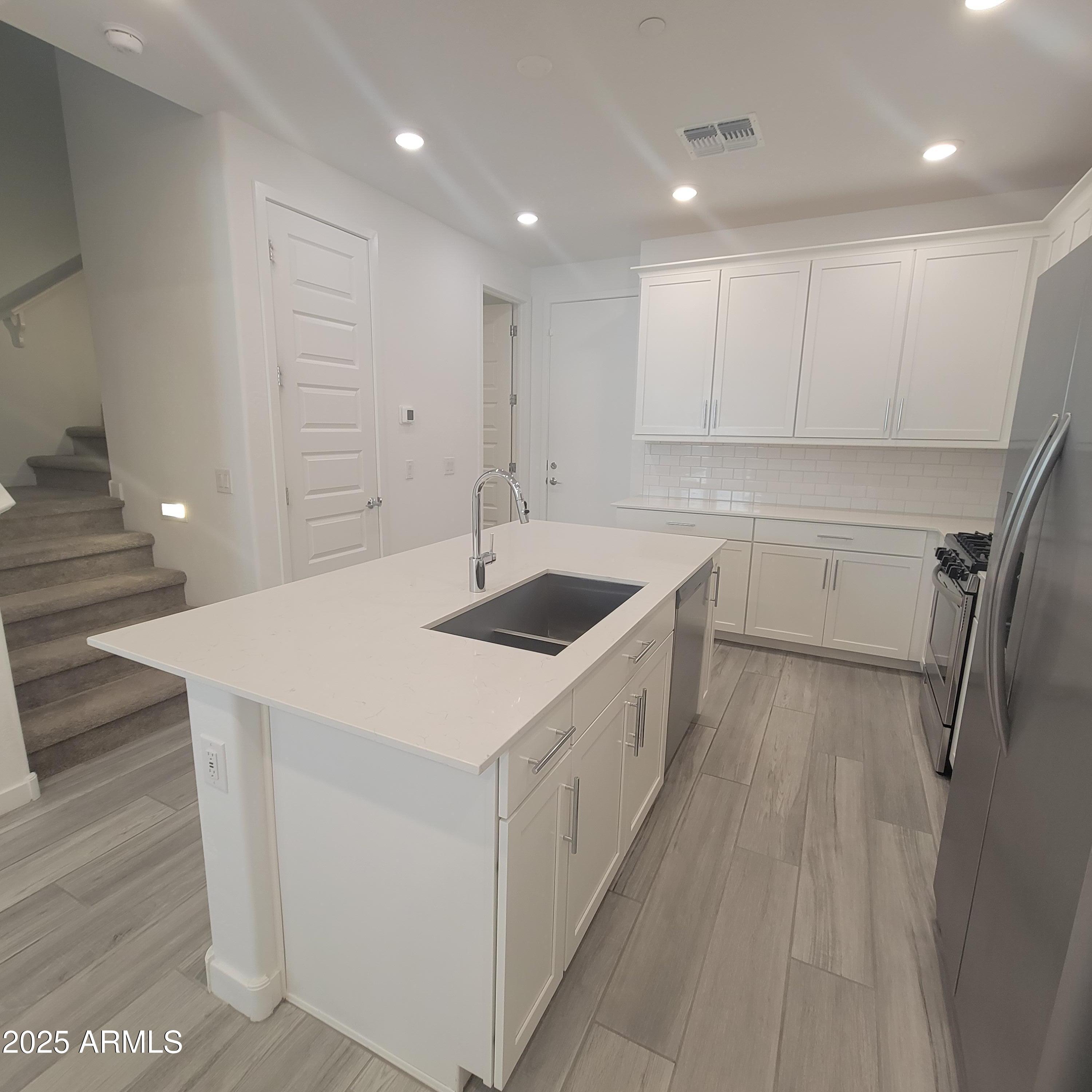 4077 South Sabrina Drive, Unit 30 Chandler, AZ 85248 - Photo 6 of 37 a kitchen with a sink a stove a refrigerator and white cabinets
