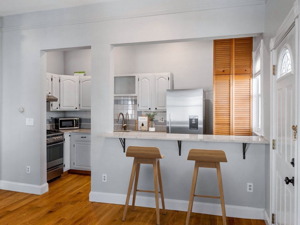 58 Telegraph Street, Unit 2 Boston, MA 02127 - Photo 5 of 17 a kitchen with stainless steel appliances granite countertop a stove top oven a sink and white cabinets with wooden floor
