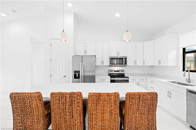 a kitchen with stainless steel appliances granite countertop a refrigerator a sink a stove with white cabinets