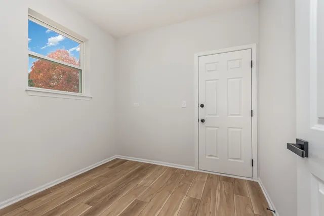 a view of an empty room with wooden floor and a painting