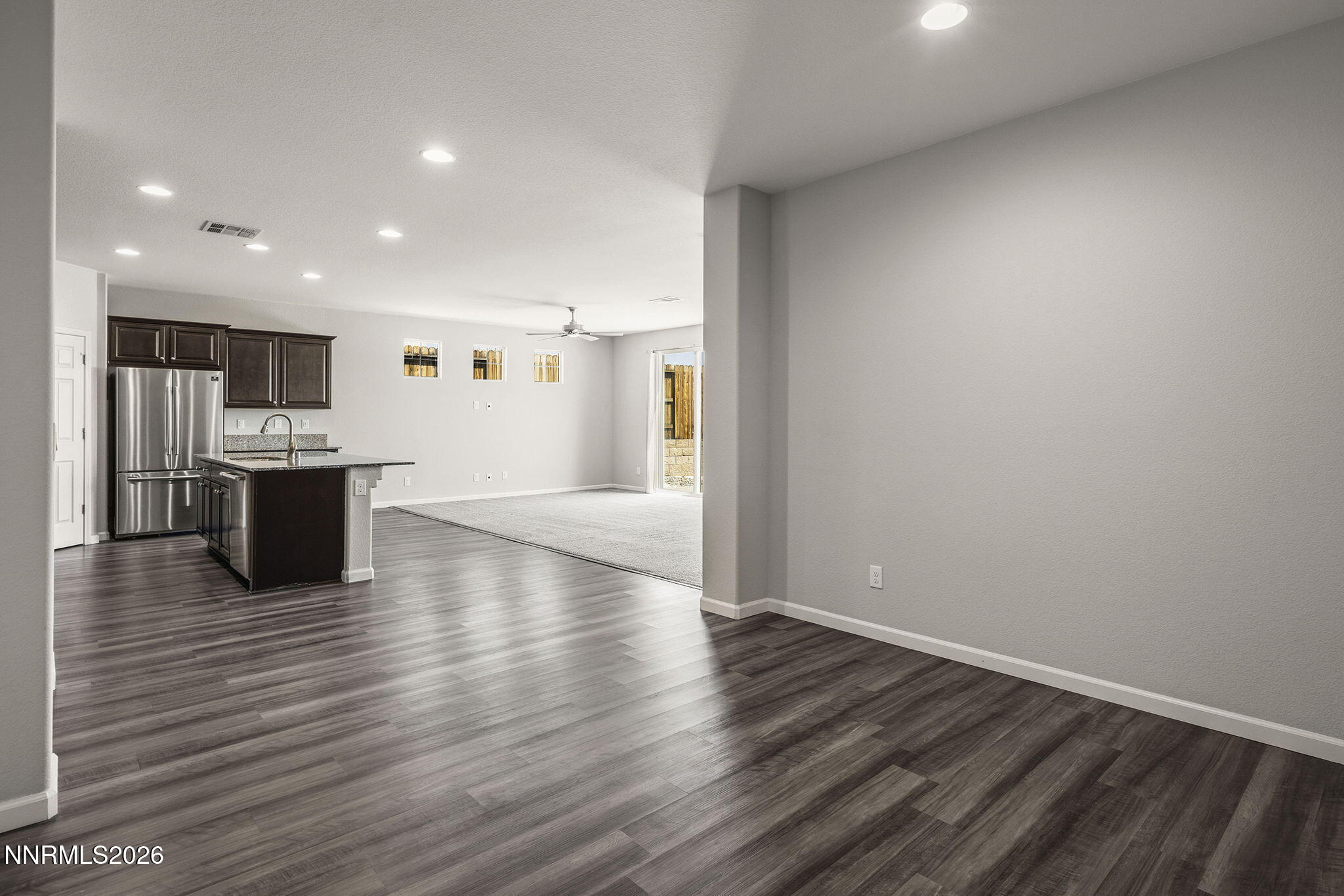 14138 Glowing Amber Court Reno, NV 89511 - Photo 18 of 36 an empty room with wooden floor and a kitchen