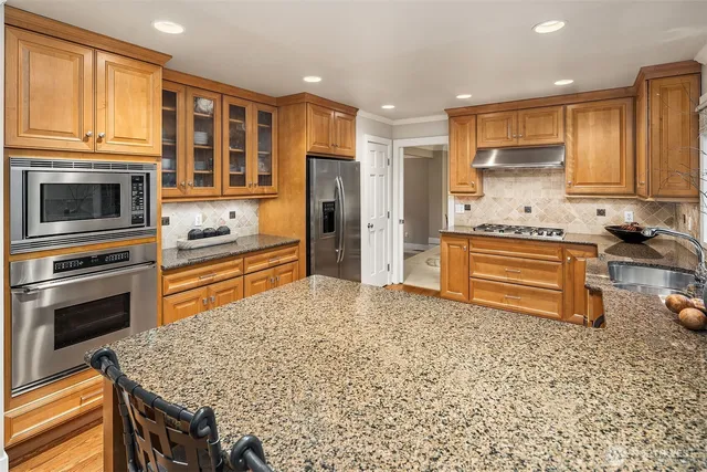 a kitchen with stainless steel appliances granite countertop a stove refrigerator and cabinets