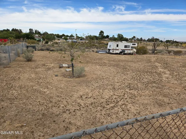 a view of a dry yard with wooden fence