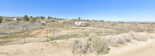 a view of a dry yard with wooden fence