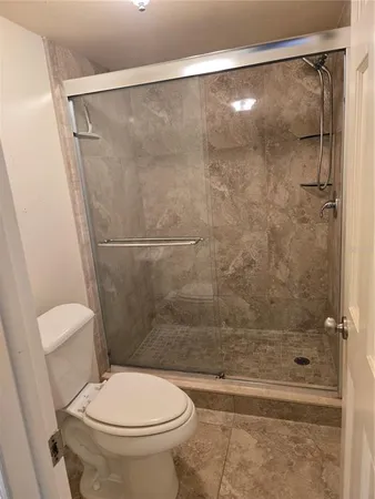 a white toilet sitting next to a bath tub and a shower