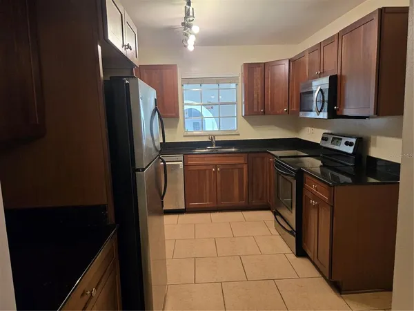 a kitchen with stainless steel appliances granite countertop a refrigerator a sink a stove top oven and a dishwasher