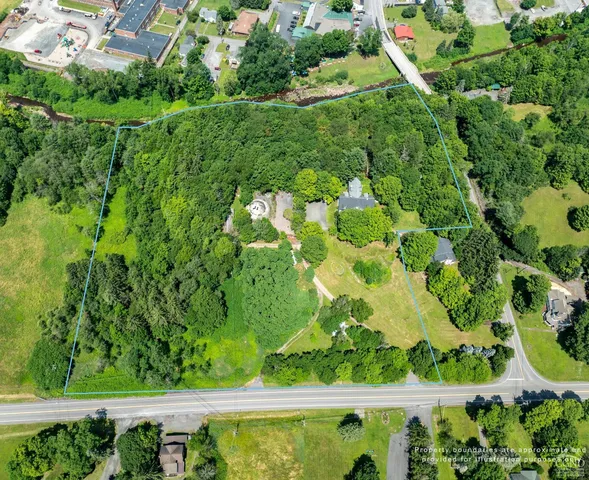 an aerial view of residential houses with outdoor space and trees