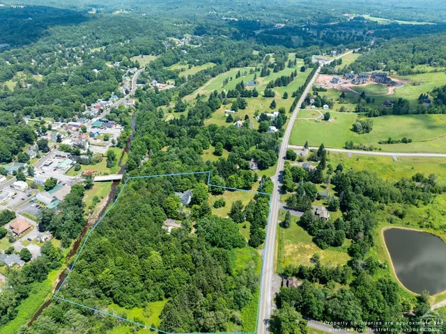 an aerial view of residential house with outdoor space and trees all around