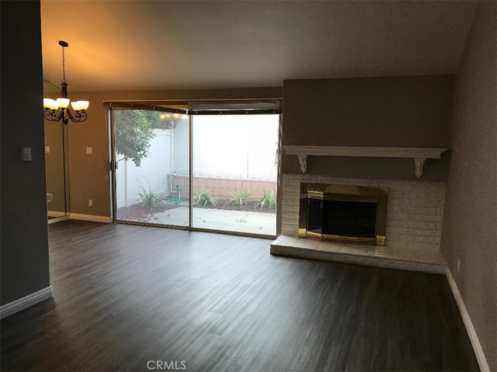 an empty room with wooden floor fireplace and windows