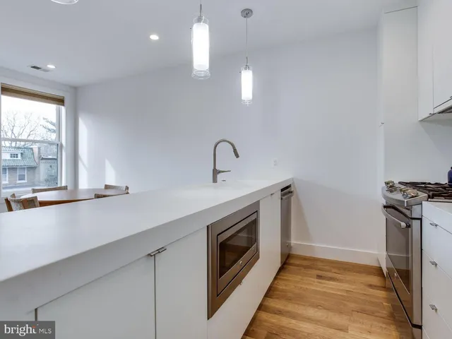 a kitchen with stainless steel appliances granite countertop a sink a stove and a wooden floors