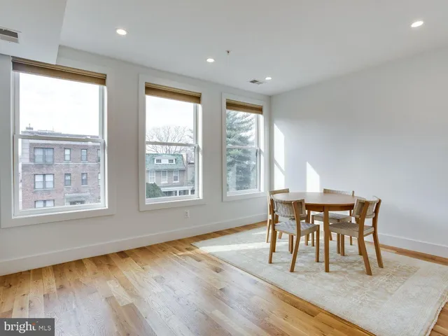 a dining room with wooden floor and a floor to ceiling window
