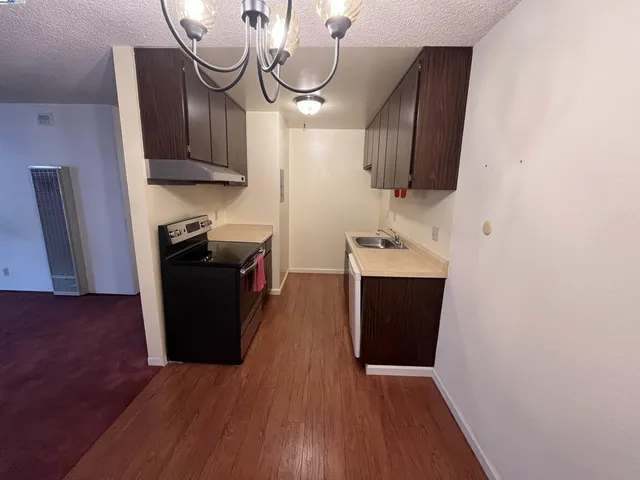 a view of a kitchen with wooden floor and cabinets