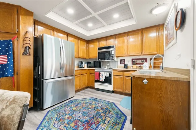 a kitchen with a refrigerator a sink dishwasher with a dining table and chairs with wooden floor