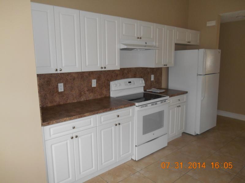 926 Falling Water Road Weston, FL 33326 - Photo 8 of 24 a kitchen with white cabinets and white appliances