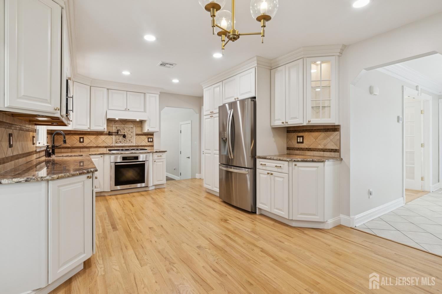 3 Cedar Lane Milltown, NJ 08850 - Photo 12 of 67 a kitchen with stainless steel appliances granite countertop a refrigerator a stove oven a sink dishwasher and white cabinets with wooden floor