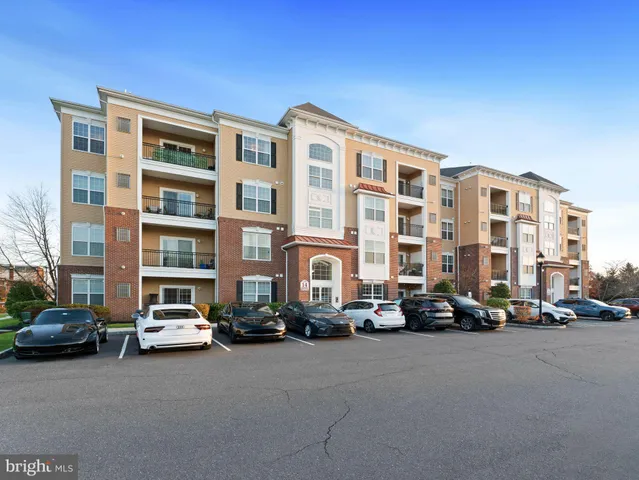 a front view of a residential apartment building with cars parked