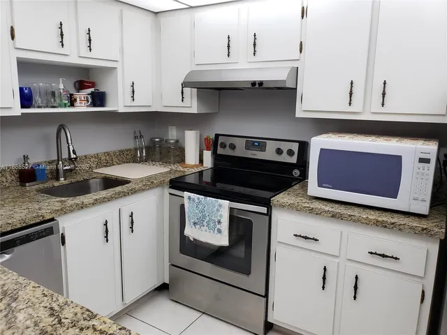 a kitchen with granite countertop white cabinets and white appliances