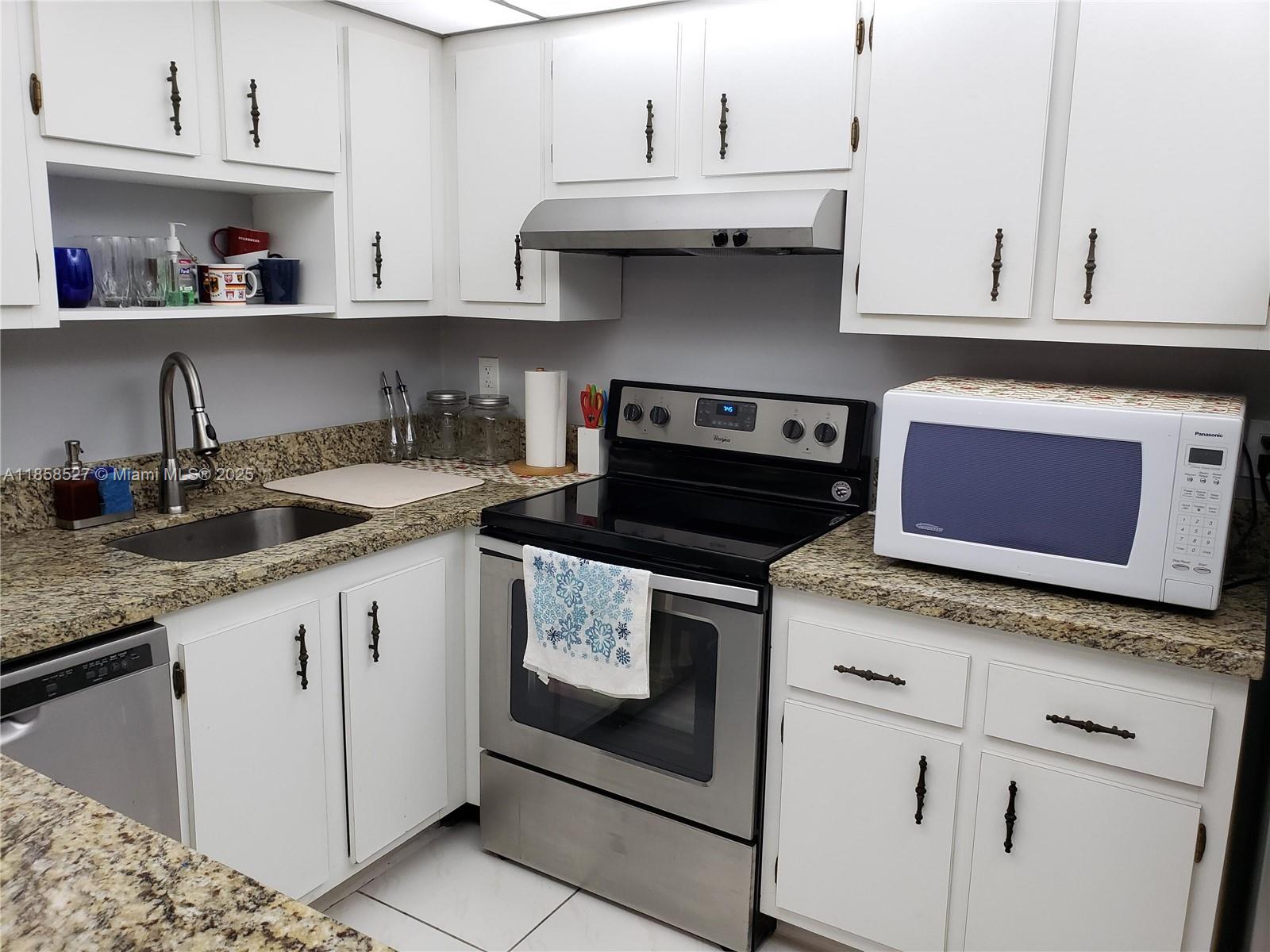 a kitchen with granite countertop white cabinets and white appliances