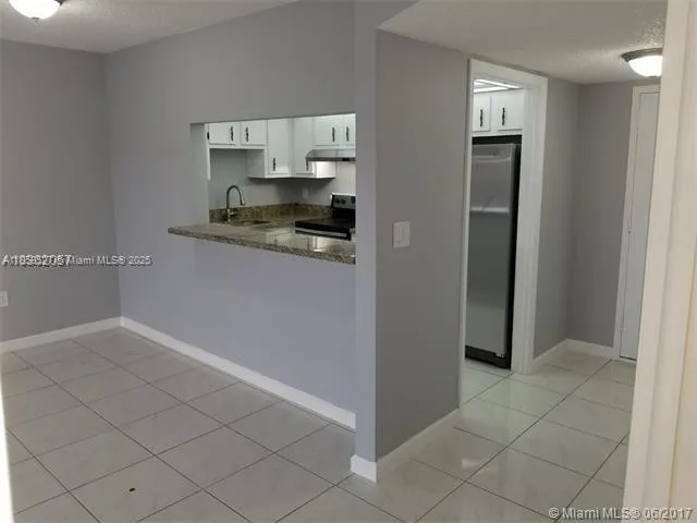 a living room with stainless steel appliances granite countertop a refrigerator and a sink
