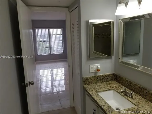 a bathroom with a granite countertop sink a mirror and shower