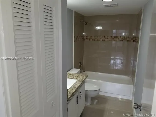 a bathroom with a granite countertop sink a toilet and shower
