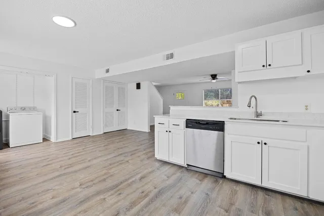 a kitchen with granite countertop white cabinets and wooden floor