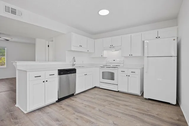 a kitchen with cabinets stainless steel appliances and wooden floor
