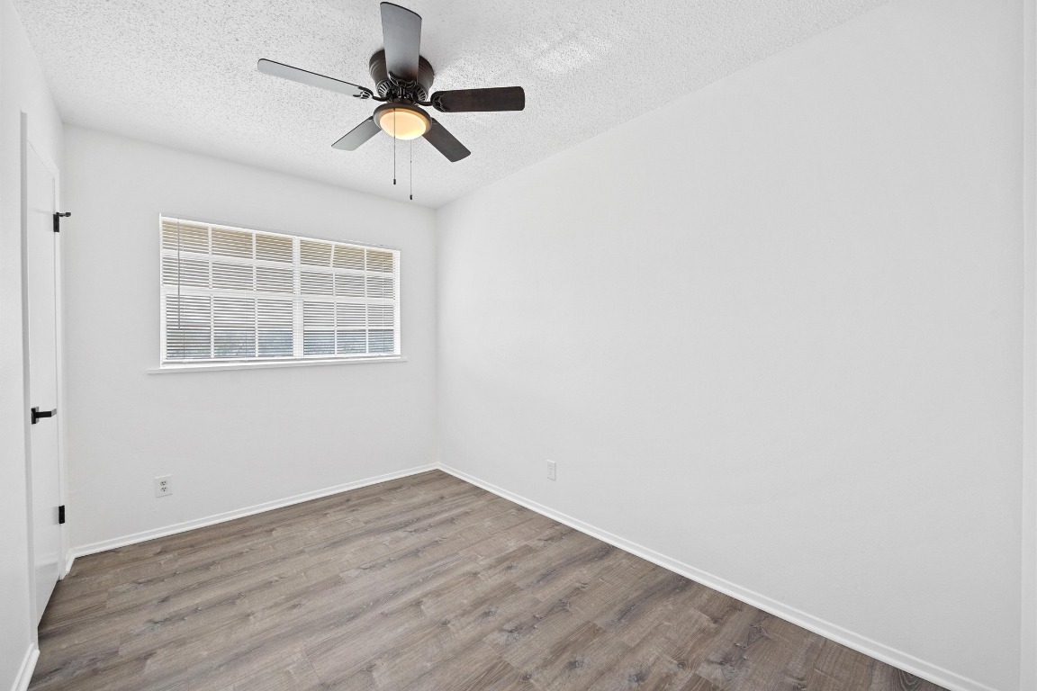 5211 Thunderbird Street, Unit A Lago Vista, TX 78645 - Photo 20 of 26 an empty room with wooden floor chandelier fan and windows