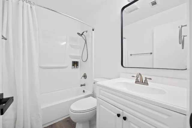 an empty room with wooden floor chandelier fan and windows