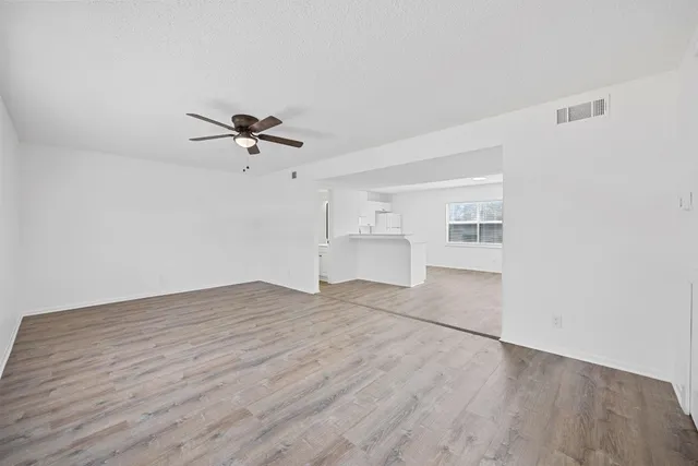 a view of empty room with wooden floor and ceiling fan
