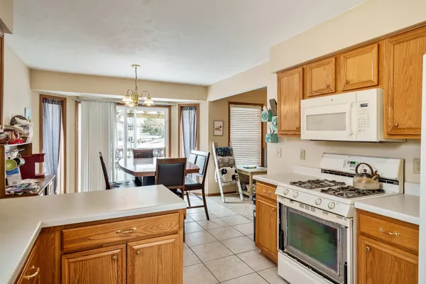 a kitchen with stainless steel appliances a stove a sink a refrigerator a dining table and chairs with wooden floor