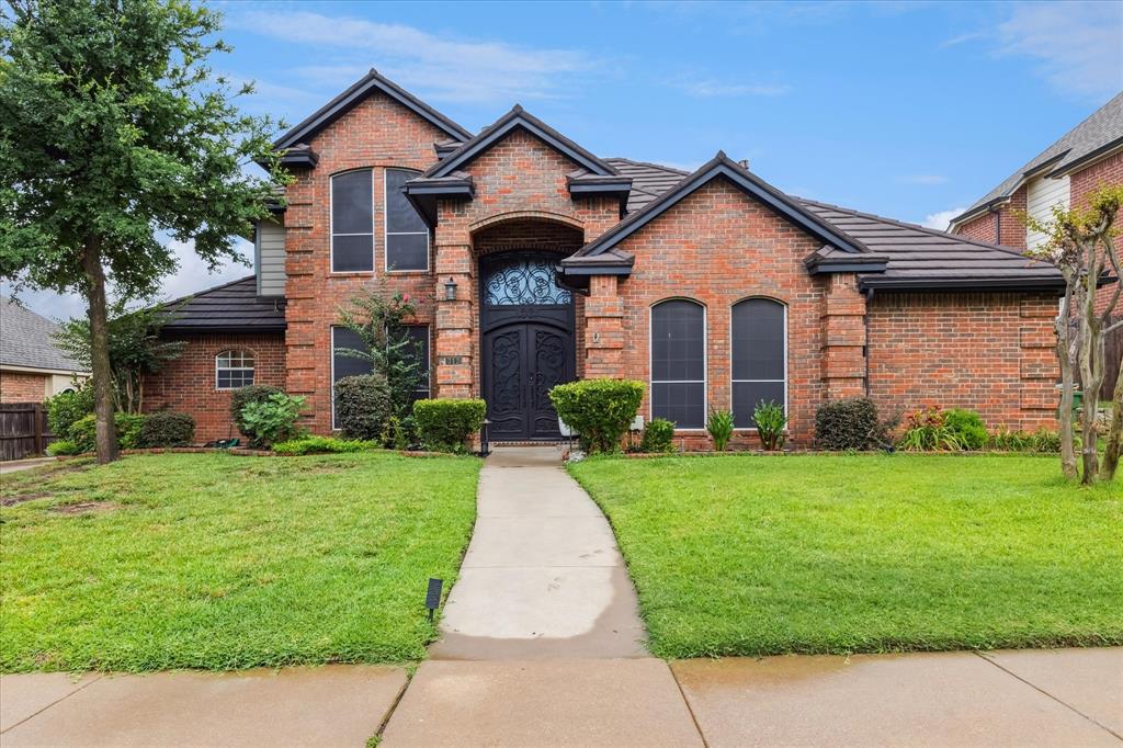 French provincial home with brick siding and a front yard