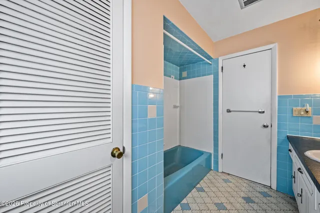 a bedroom with a bed a dresser and paintings on the wall