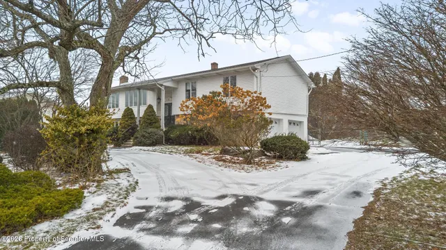 a view of a white house with a yard covered with snow and trees