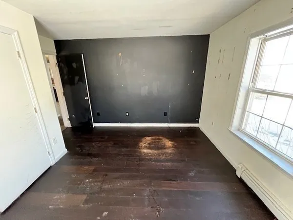 a view of an empty room with wooden floor and windows