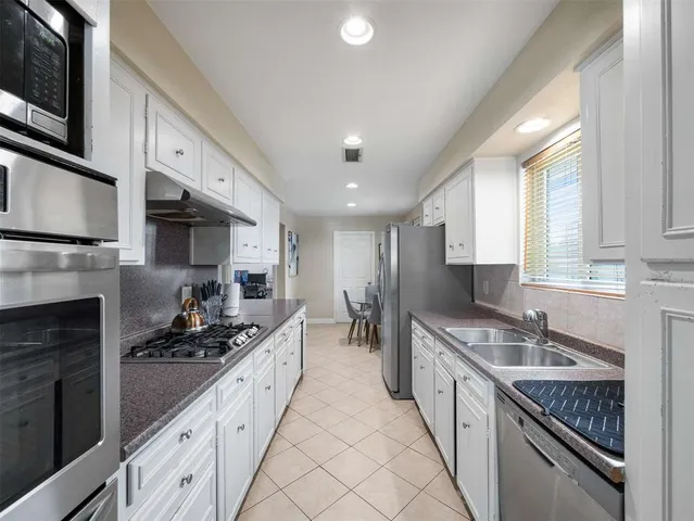 a large kitchen with stainless steel appliances granite countertop a stove a sink and a microwave