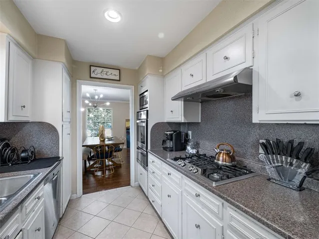 a kitchen with granite countertop a sink a stove and cabinets