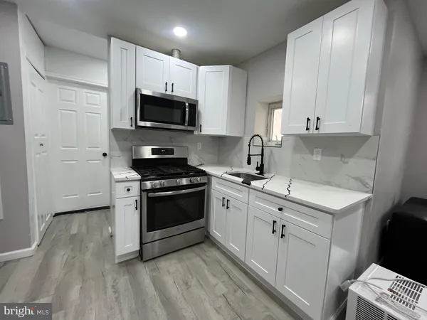 a kitchen with stainless steel appliances a sink dishwasher a stove and a microwave oven on granite countertops