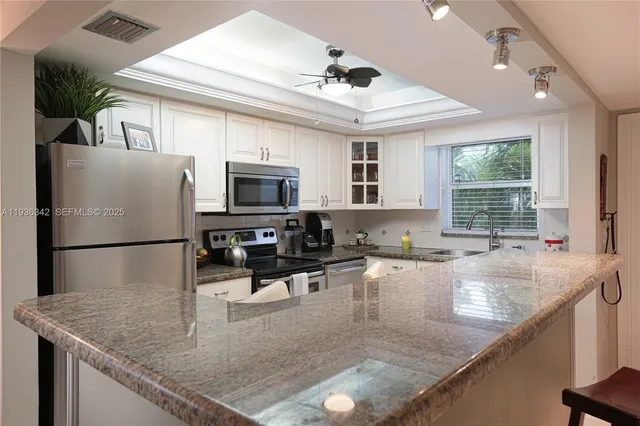 a kitchen with stainless steel appliances granite countertop a sink a stove and a refrigerator