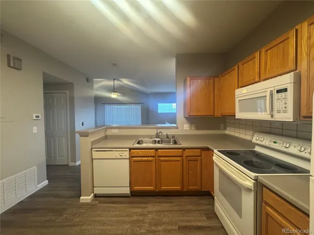 a view of a kitchen counter space a sink wooden floor and a window
