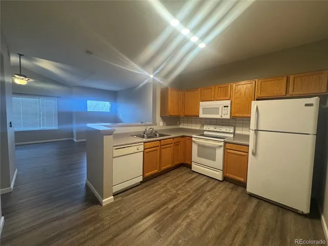 a kitchen with a refrigerator stove and wooden floor