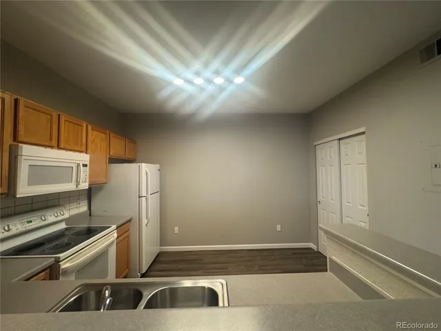 a view of a kitchen with a stove wooden cabinets and a refrigerator