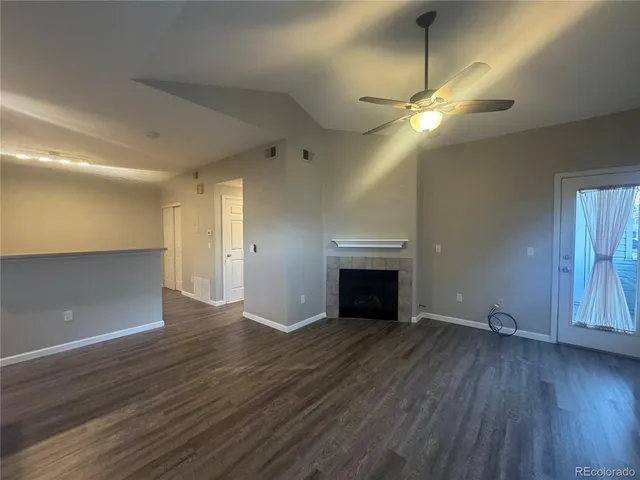 an empty room with wooden floor fireplace and windows