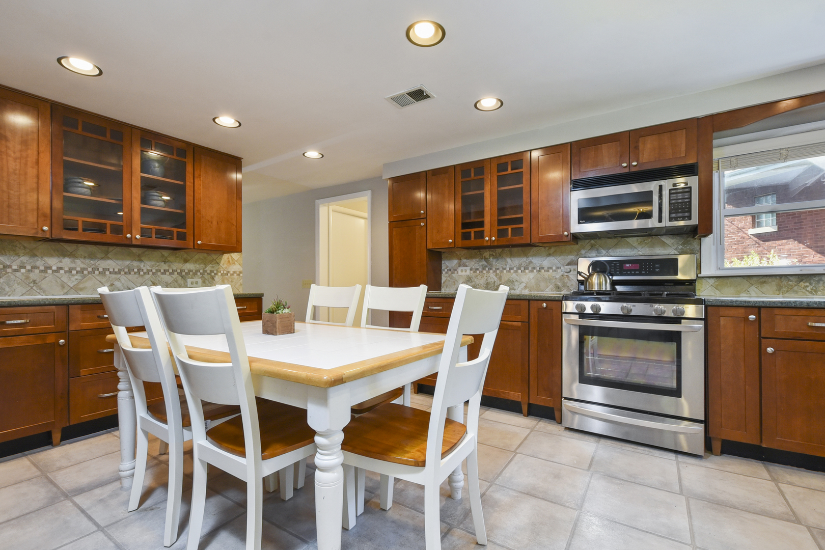 345 Olmsted Road Riverside, IL 60546 - Photo 3 of 31 a kitchen with stainless steel appliances kitchen island granite countertop a stove a sink a microwave and a dining table
