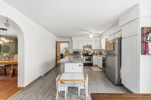 a living room with stainless steel appliances furniture wooden floor and a view of kitchen