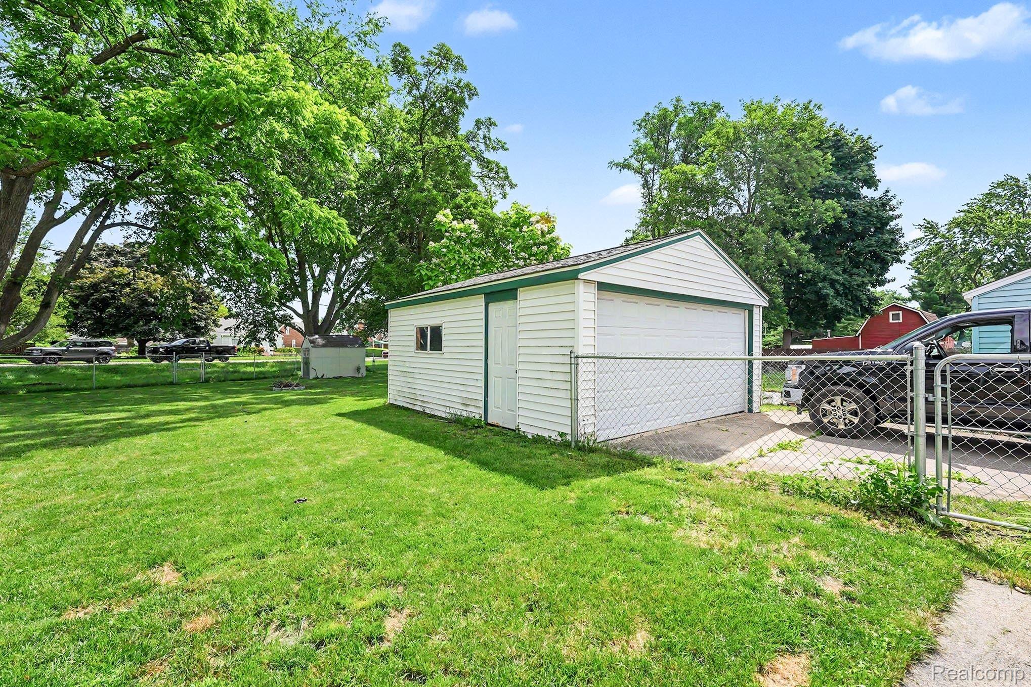 8215 Clinton River Road Sterling Heights, MI 48314 - Photo 26 of 28 Detached garage with white siding, green trim, and a white garage door