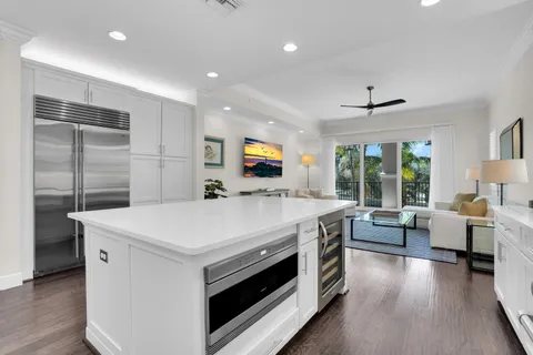 a kitchen with stainless steel appliances granite countertop a stove a sink a refrigerator and a dining table with wooden floor